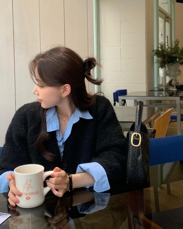 Áo sơ mi xanh pastel layering cùng cardigan len đen oversized – công thức “lười mà sang” của giới fashionista mùa thu. Chỉ cần khéo léo xắn tay áo đã sở hữu ngay outfit café cuối tuần cực cuốn, vừa ấm áp vừa phóng khoáng.