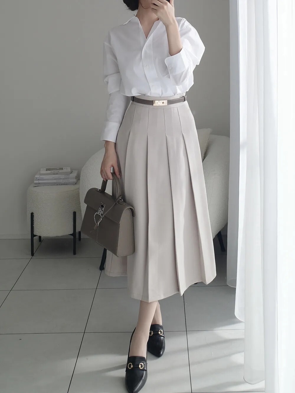 Combo sơ mi và váy chữ A lưng cao giúp vóc dáng cân đối, đôi chân dài hơn. Đây là lựa chọn vừa thanh lịch, vừa nữ tính. Sơ mi trắng cơ bản hay họa tiết nhẹ nhàng đều dễ phối, đi cùng giày slingback hoặc cao gót là chuẩn công sở.