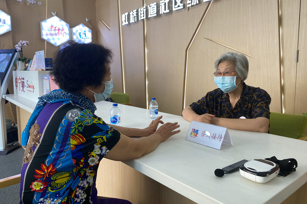 Chen Wenhua trả lời các câu hỏi của một cư dân địa phương khi làm lễ tân ở trung tâm người cao tuổi Hồng Kiều, ngày 19/8. Ảnh: Sixthtone
