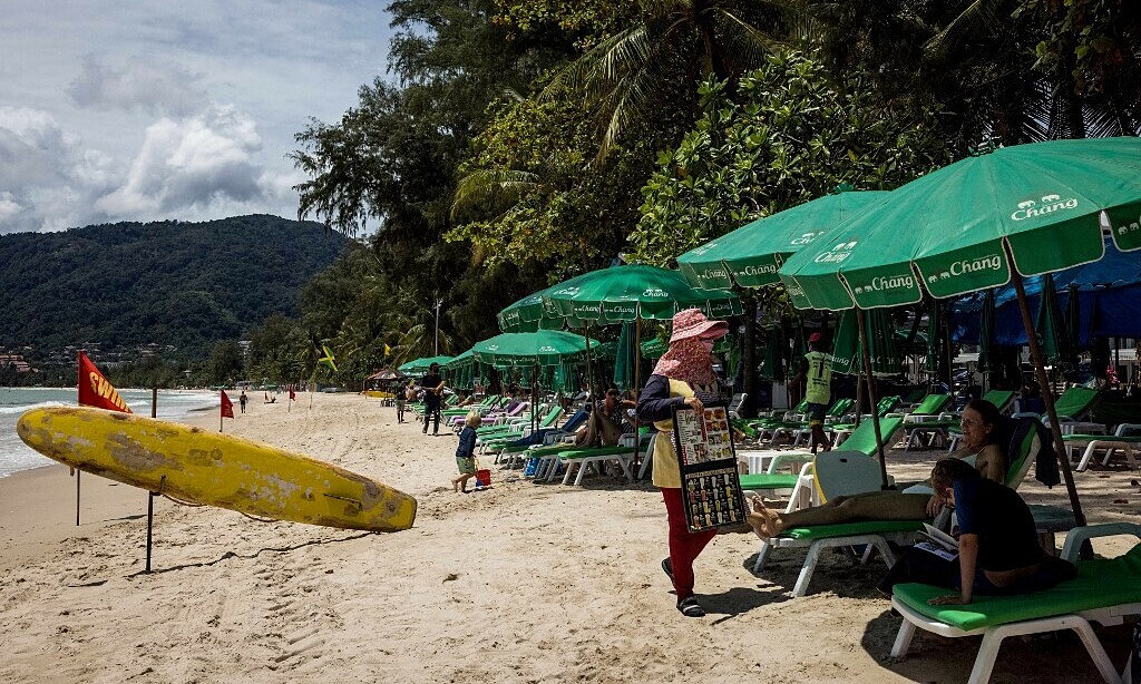 Người bán hàng và du khách trên bãi biển ở Phuket, Thái Lan, hồi tháng 8. Ảnh: AFP.