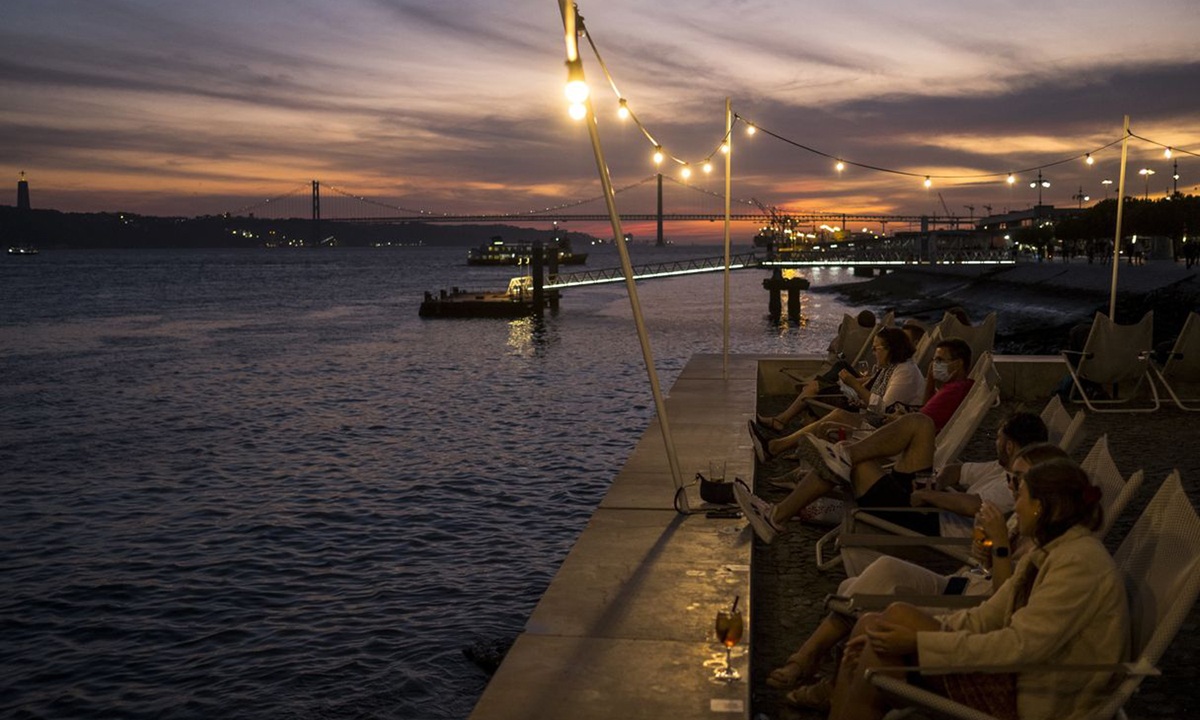 Du khách ngắm hoàng hôn bên bờ sông Tagus ở Lisbon tuần trước. Ảnh: WSJ.