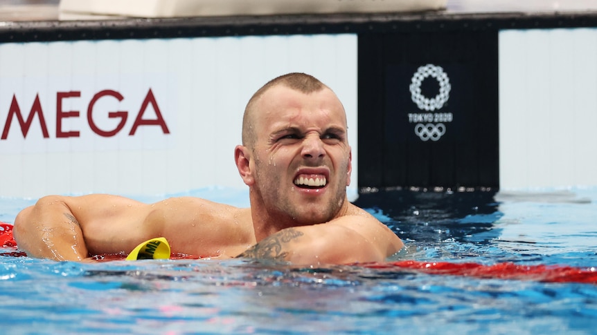 An Australian male swimmer leans over the ropes after his heat at the Tokyo Olympics.