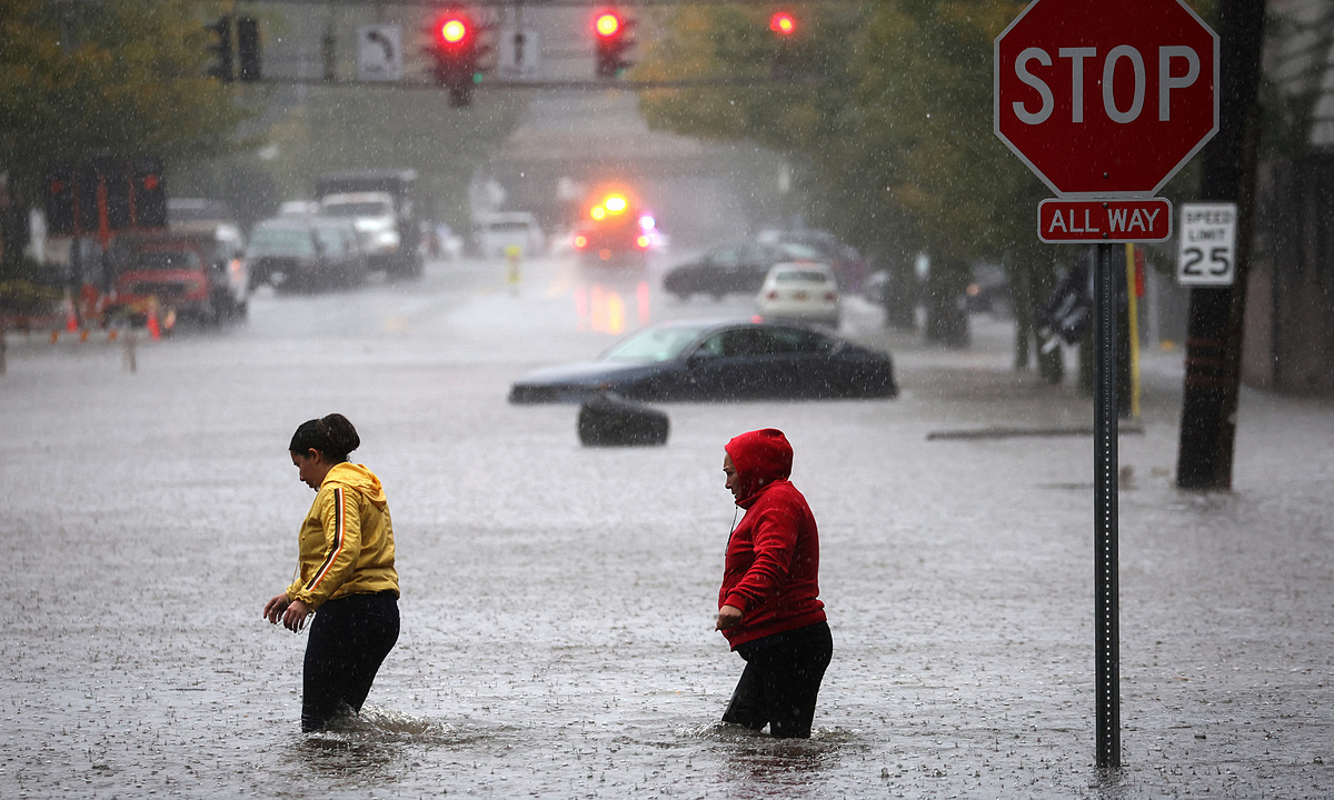 Người dân đi qua một tuyến đường bị ngập sau trận mưa lớn tại Mamaroneck, bang New York ngày 29/9. Ảnh: Reuters
