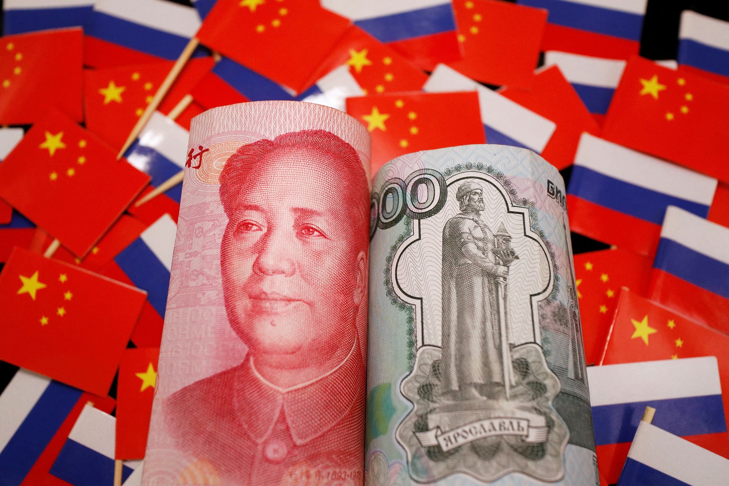 Tiền giấy nhân dân tệ và rouble trên nền quốc kỳ Trung Quốc và Nga. Ảnh: Reuters