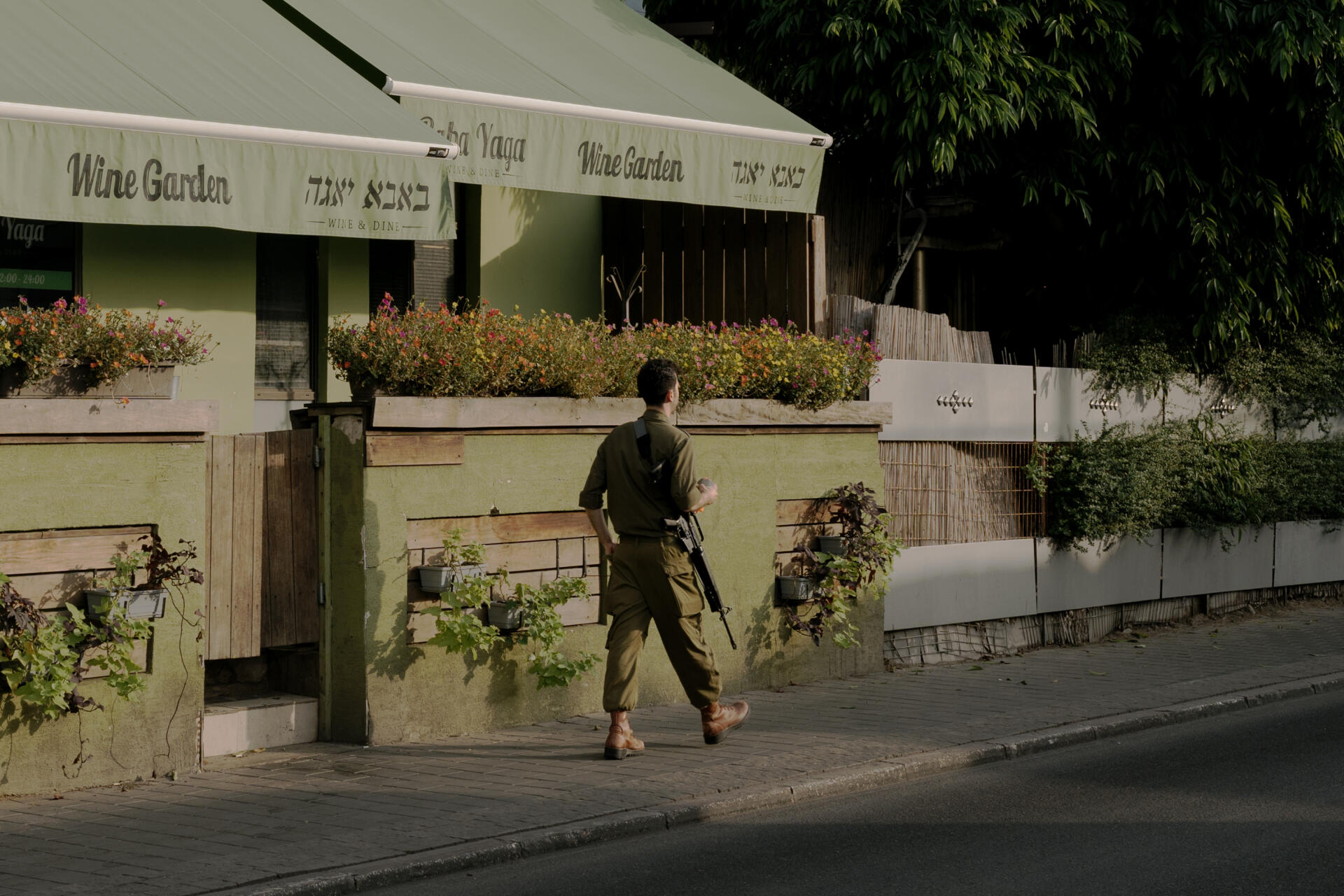 Một người lính đi qua một nhà hàng đóng cửa ở Tel Aviv ngày 23/10. Ảnh: Le Monde