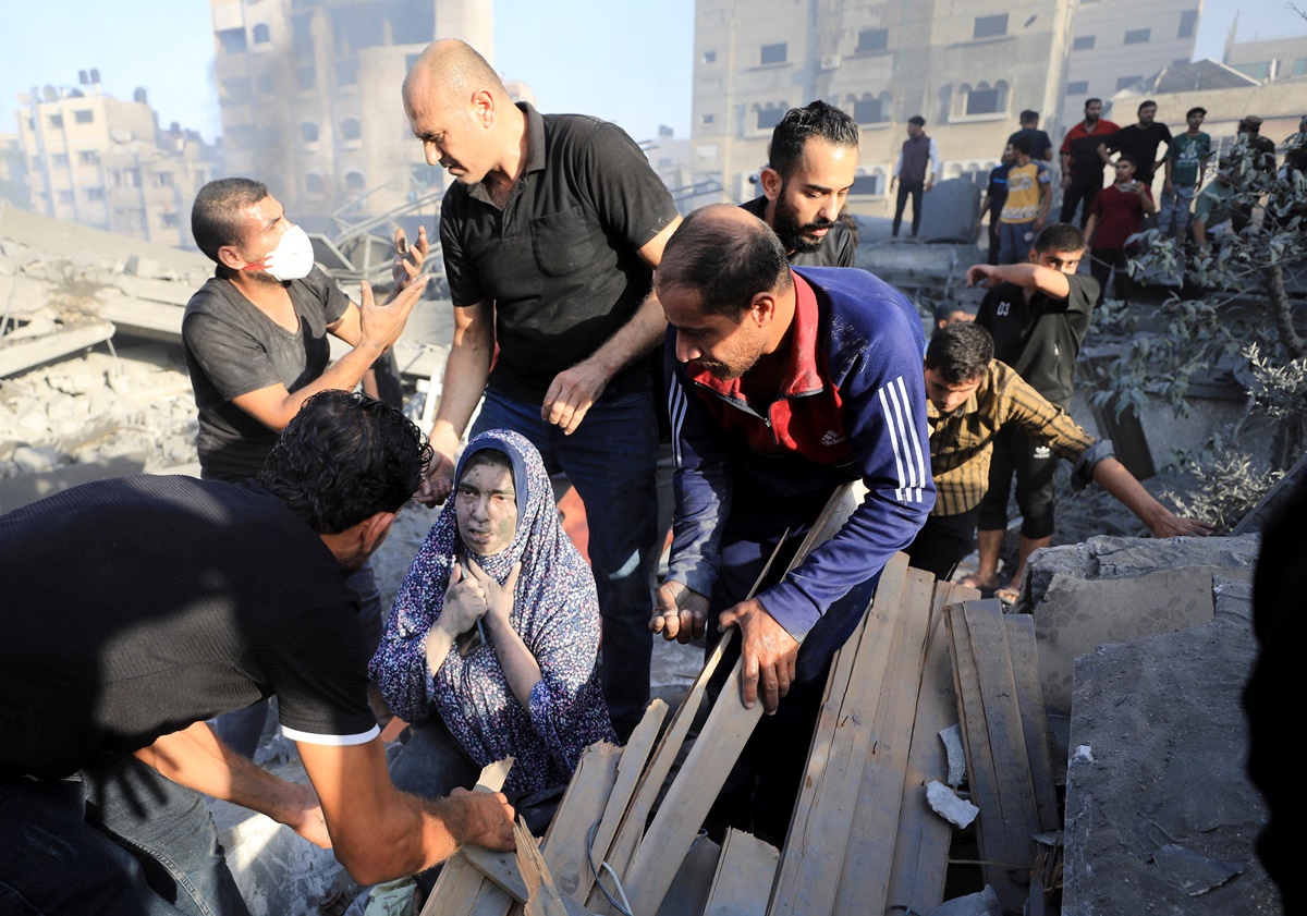 Người dân được hỗ trợ rời khỏi đống đổ nát của một tòa nhà bị trúng tên lửa ở thành phố Gaza hôm 25/10. Ảnh: Reuters