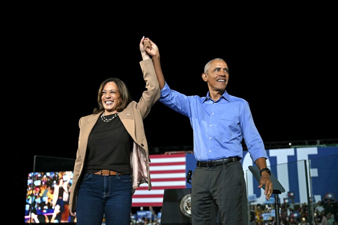 Former US President Barack Obama hold hands with US Vice President and Democratic presidential candidate Kamala Harris during a campaign rally at the James R Hallford Stadium in Clarkston, Georgia on October 24, 2024.