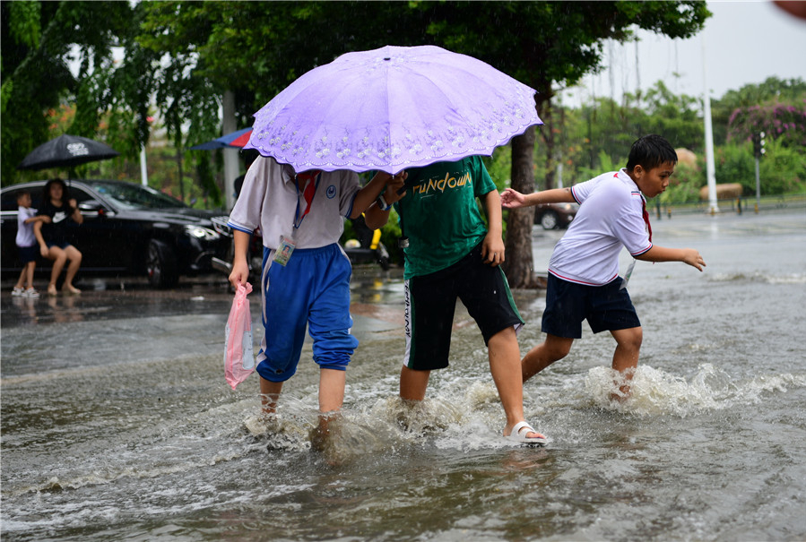 Người đi đường lội qua con đường ngập nước vì bão ở Tam Á, tỉnh Hải Nam hồi tháng 7/2019. Ảnh: China Daily