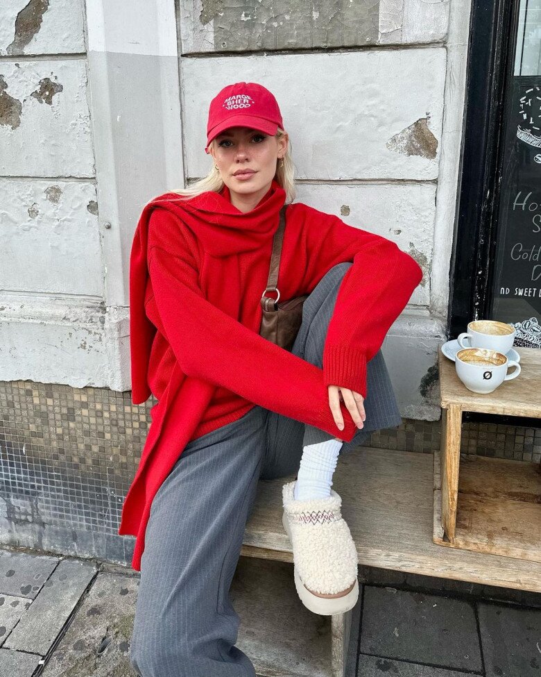 Áo len đỏ rực và mũ lưỡi trai ton-sur-ton tạo nên điểm nhấn nổi bật, trong khi quần xám tro đóng vai trò làm nền, giúp sắc đỏ thêm nổi bật mà không chói mắt.