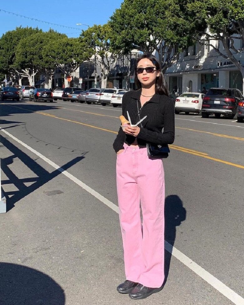 Sự kết hợp giữa quần hồng và áo dệt kim đen trông phá cách, trẻ trung.