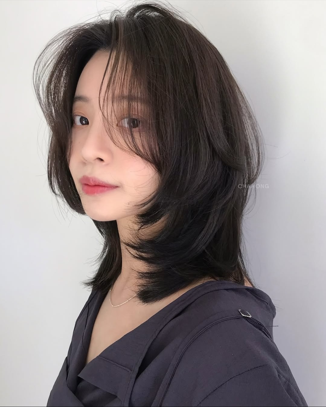 Tóc ngắn cá tính kết hợp với mái bay giúp gương mặt tròn trông thon gọn hơn nhờ hiệu ứng ôm nhẹ hai bên má. Tóc đen làm nổi bật đường nét khuôn mặt, tăng vẻ sắc sảo nhưng vẫn giữ sự dịu dàng. Đây là kiểu tóc đang rất hot hiện nay.