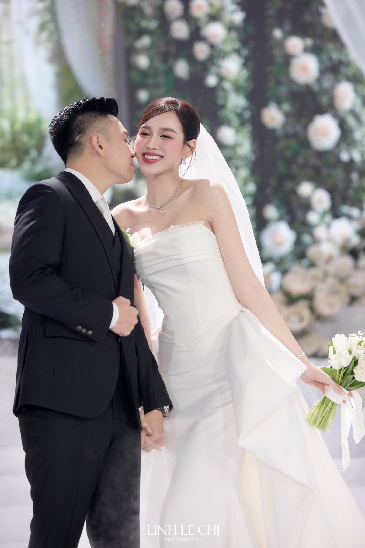 Với phom dáng đuôi cá, thân váy được xử lý để ôm nhẹ phần eo và hông, sau đó bung xòe dần về phía chân váy để tôn vóc dáng và giúp nàng dâu dễ di chuyển. Điểm nhấn ở phần eo được tạo hình tựa đôi cánh nơ.