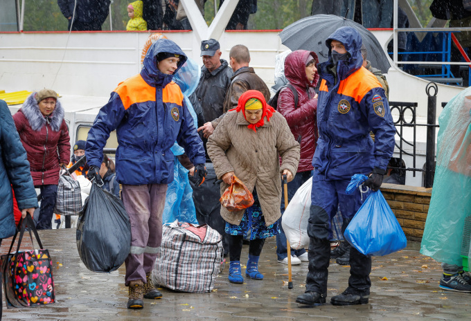 Người dân sơ tán từ thành phố Kherson từ phà đi lên xe buýt ở thị trấn Oleshky, tỉnh Kherson, để đến Crimea ngày 23/10. Ảnh: Reuters.