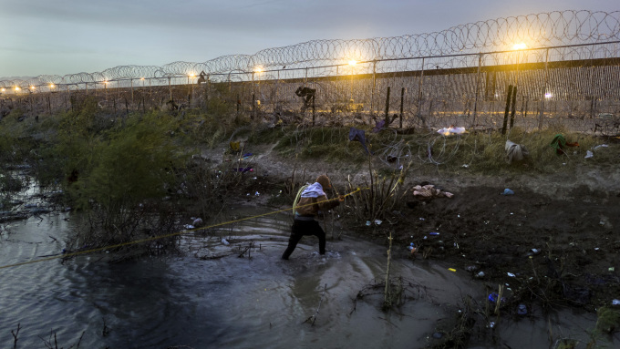 Một người nhập cư Venezuela đang tìm cách vượt hàng rào thép gai để từ Mexico vào thành phố El Paso, bang Texas, Mỹ ngày 13/3. Ảnh: AFP