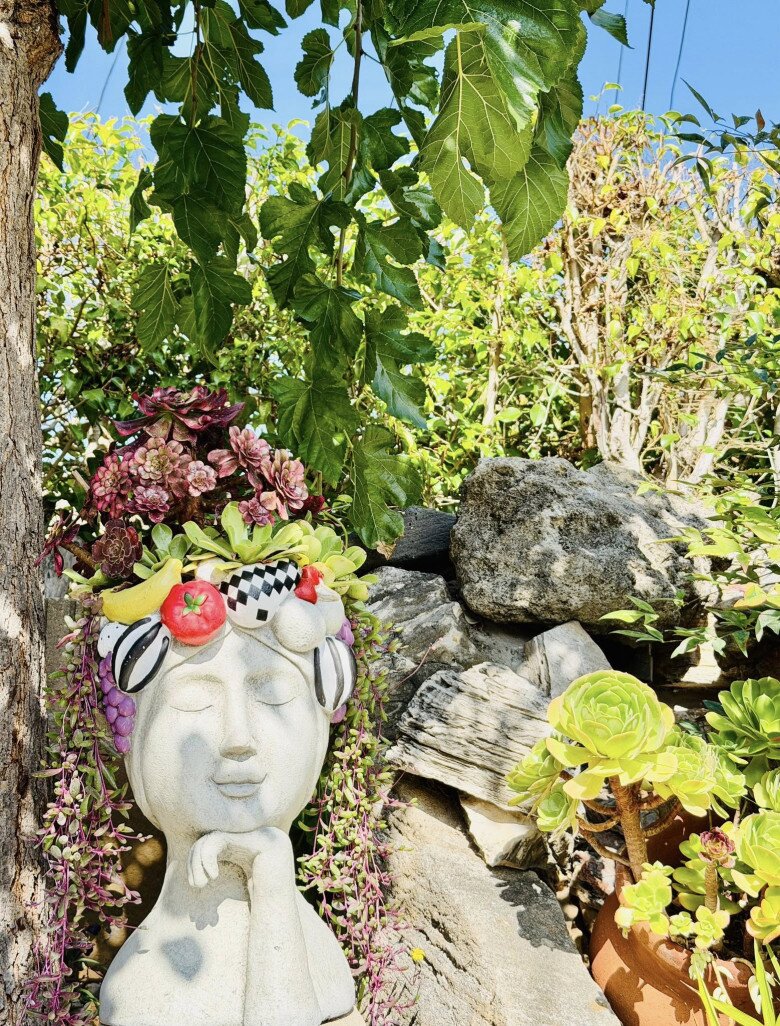 Nữ danh hài làm duyên bắt chước bức tượng cô gái. Tượng cô gái với mái tóc làm từ hoa đá và trái cây giả là một điểm nhấn sáng tạo trong khu vườn của Thúy Nga. Đặt bên gốc cây và mảng đá xếp tự nhiên, bức tượng vừa vui mắt vừa thể hiện gu thẩm mỹ tinh nghịch, gần gũi của chủ nhân.