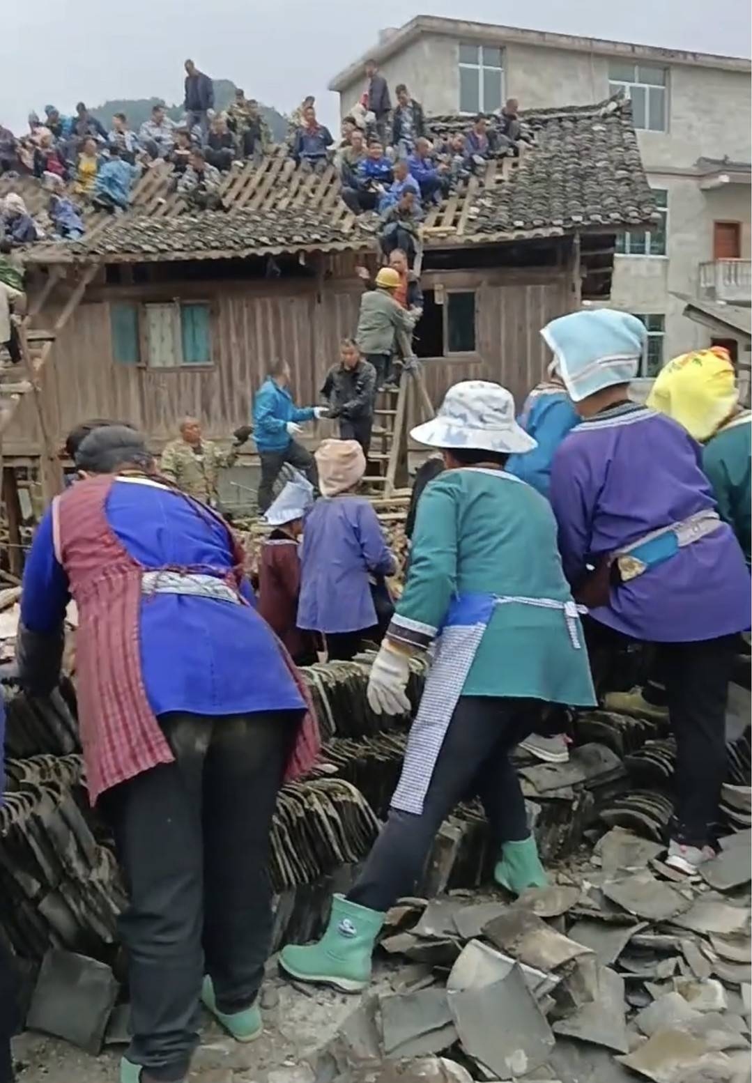 Dân làng hỗ trợ dỡ ngói trước khi di chuyển ngôi nhà gỗ 6 tấn, ở Quý Châu, hôm 5/11. Ảnh: Cover