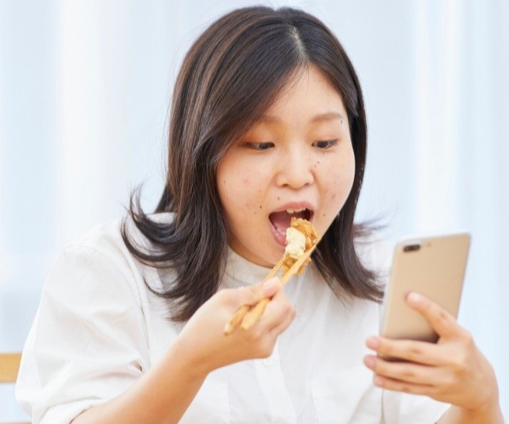 Vừa ăn vừa xem điện thoại khiến hệ tiêu hóa phải hoạt động quá mức, dễ gây đầy bụng và khó tiêu (Ảnh minh họa)