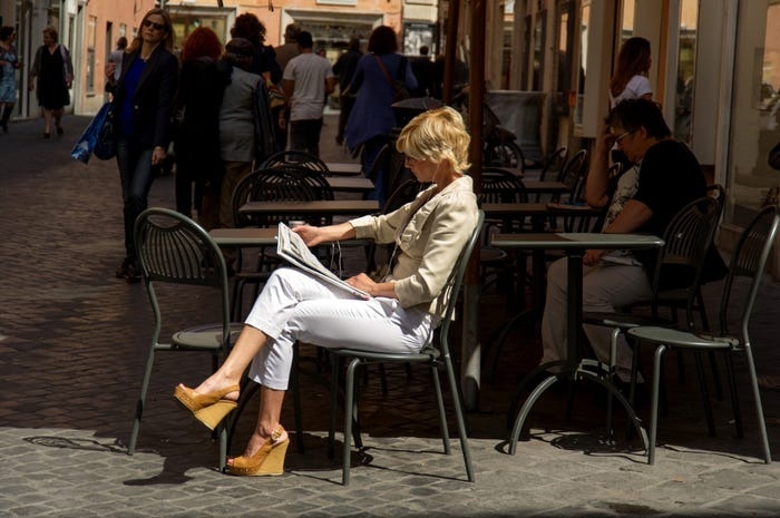 Một cô gái đang thưởng thức nhịp sống chậm rãi, thư thái với cà phê sáng, đọc báo giấy ở Lazio, Italy, tháng 10/2024. Ảnh: Business Insiders
