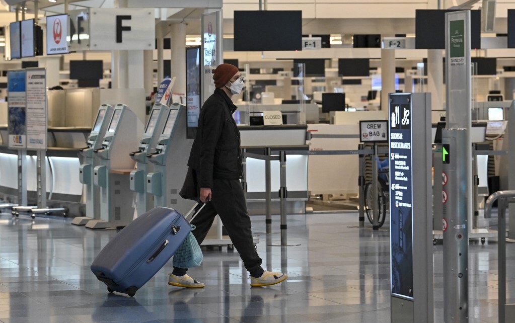 Nam hành khách đi ngang quầy làm thủ tục tại ga quốc tế, sân bay Haneda, Tokyo hôm 1/12. Ảnh: AFP.