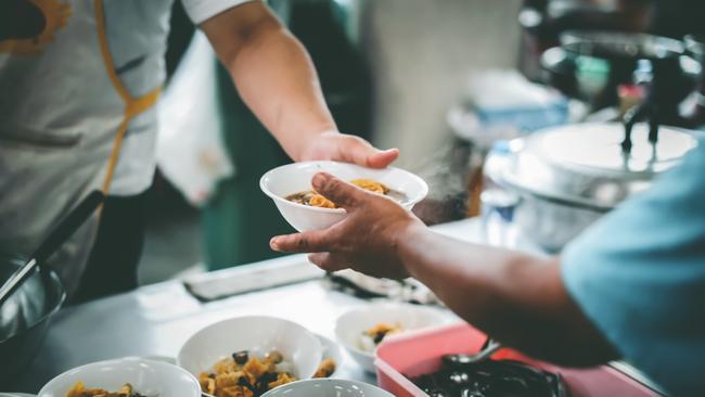 File image of a person passing a plate of food to another. 