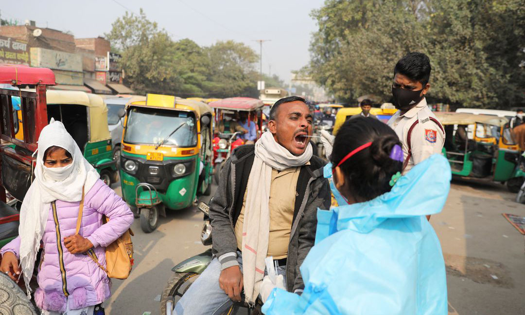 Nhân viên y tế lấy mẫu xét nghiệm nCoV trên đường phố tại New Delhi, Ấn Độ, hôm 6/12. Ảnh: Reuters.