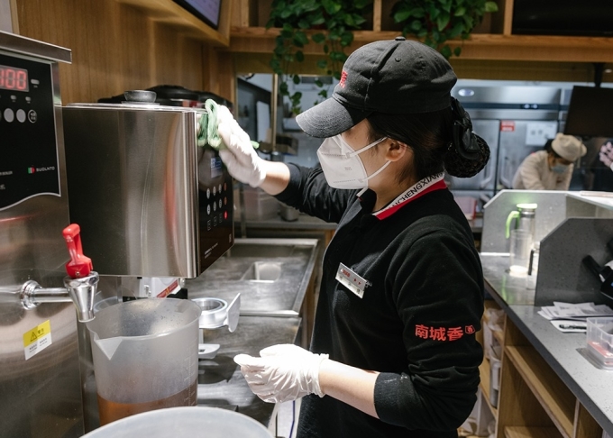 Nhân viên một nhà hàng ở Bắc Kinh lau chùi, dọn dẹp cửa tiệm chuẩn bị mở cửa đón khách ngày 6/12. Ảnh: Global Times