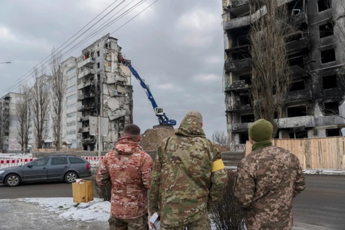 Các binh sĩ Ukraine đứng quan sát một tòa nhà bị trúng tên lửa được dỡ bỏ ở thành phố Borodyanka, gần Kiev, hôm 13/12. Ảnh: AP.