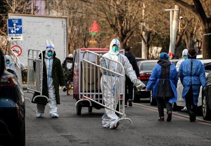 Nhân viên y tế mặc đồ bảo hộ di chuyển rào chắn tại một khu dân cư được dỡ phong tỏa Covid-19 ở Bắc Kinh, Trung Quốc, ngày 9/12. Ảnh: AFP
