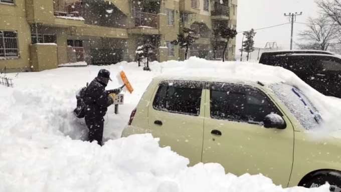 Một người dân cào tuyết quanh ô tô ở bãi đỗ xe tại thành phố Kitami, tỉnh Hokkaido, miền bắc Nhật Bản, ngày 24/12. Ảnh: AP