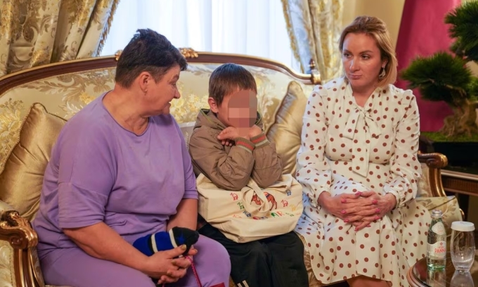 Một em nhỏ Ukraine ngồi bên cạnh bà ngoại và Ủy viên của Tổng thống Nga phụ trách quyền trẻ em Maria Lvova-Belova (phải) tại đại sứ quán Qatar ở Moskva, Nga, hôm 13/10. Ảnh: Reuters