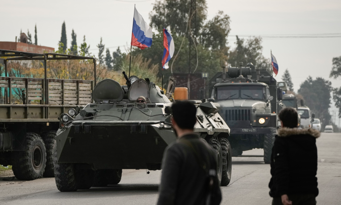 Các tay súng Syria quan sát đoàn xe Nga di chuyển gần căn cứ Hmeimim hôm 16/12. Ảnh: AP