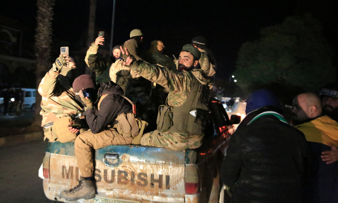 Các tay súng ngồi trên xe bán tải tiến vào thành phố Homs, Syria ngày 8/12. Ảnh: AFP