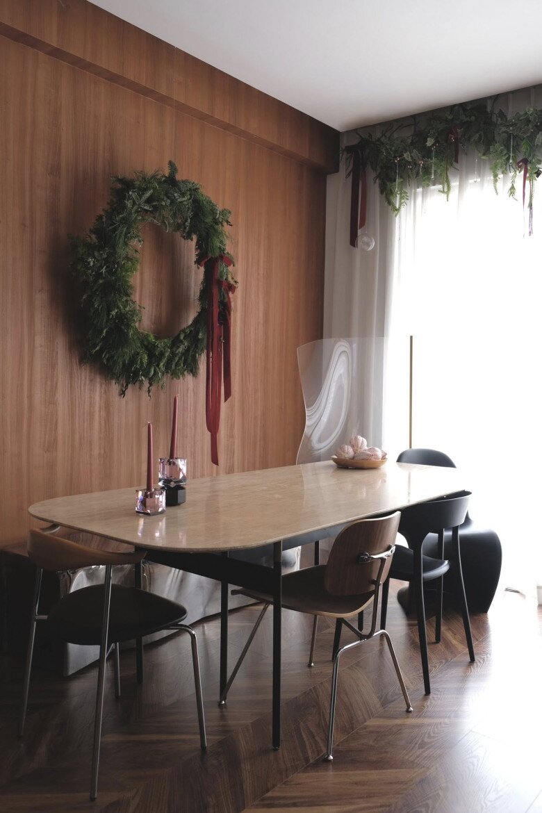 Góc bàn ăn, anh cũng đặt thêm phụ kiện trang trí bên bàn. Bức tường gỗ phía sau bàn ăn chỉ treo một vòng nguyệt quế lớn, vừa tạo không khí lễ hội vừa tránh rối mắt.
