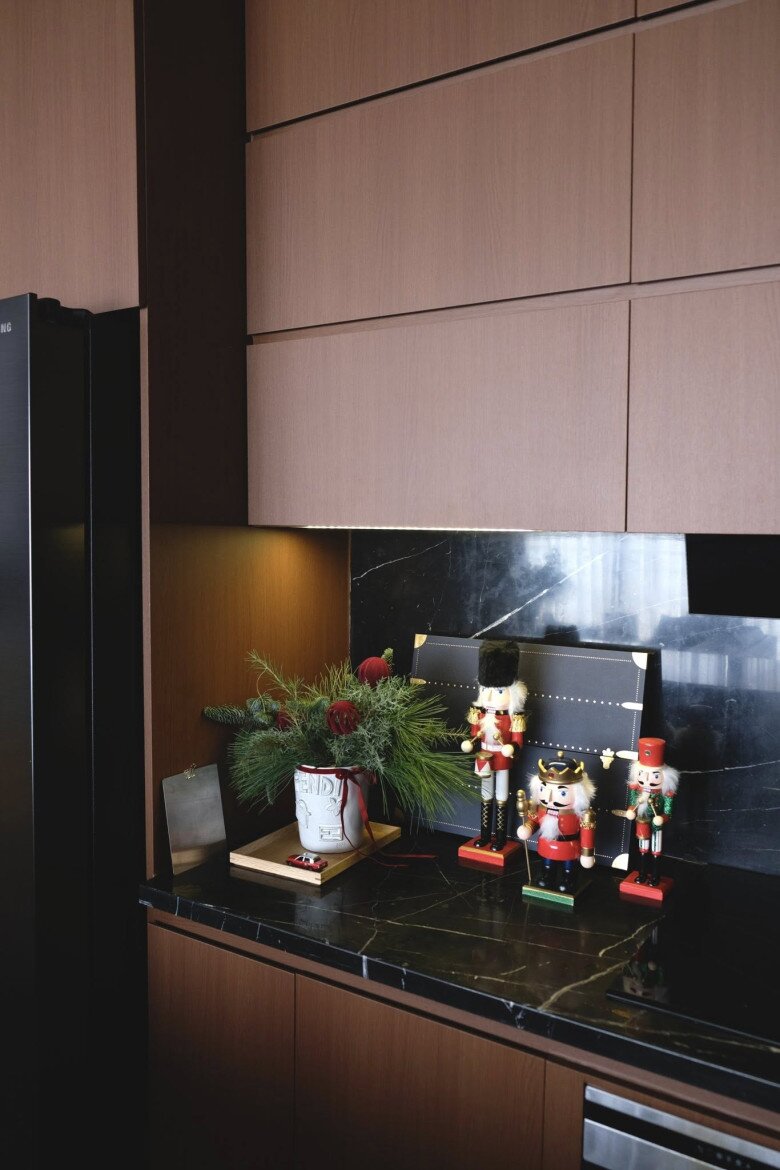 Những món decor nhỏ như lính chì, cây thông mini, bình hoa đào đông đỏ cùng những bình cành thông được đặt rải rác dọc mặt bếp, tạo sắc màu lễ hội mà vẫn giữ sự trang nhã.