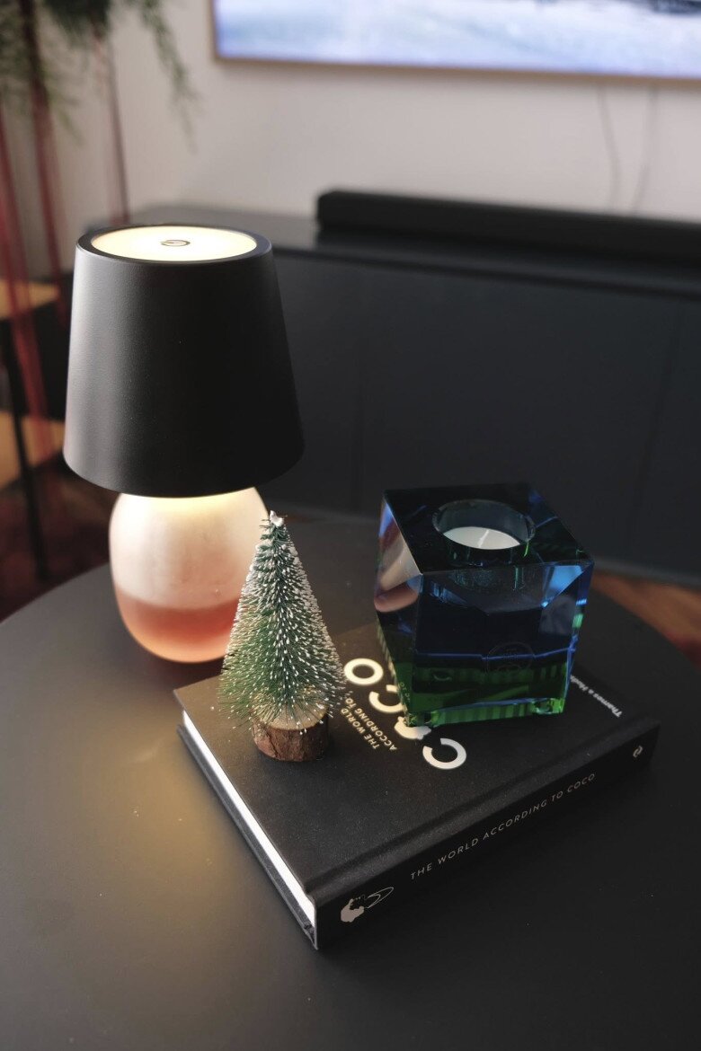 Trên bàn trà anh đặt một vài phụ kiện trang trí nhỏ với mô hình cây thông mini phủ tuyết cùng khối pha lê xanh dương, được đặt trên cuốn sách bìa cứng làm bệ đỡ. Tổng thể không gian toát lên vẻ thư thái, ấm cúng của mùa Giáng sinh.