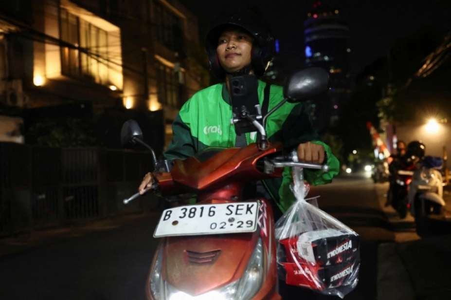Pratiwi Ariyanti, 38 tuổi, tài xế xe công nghệ Indonesia, lái xe đi sau khi nhận đơn tặng đồ ăn từ một khách hàng ở nước ngoài qua ứng dụng, tại Jakarta ngày 3/9. Ảnh: Reuters