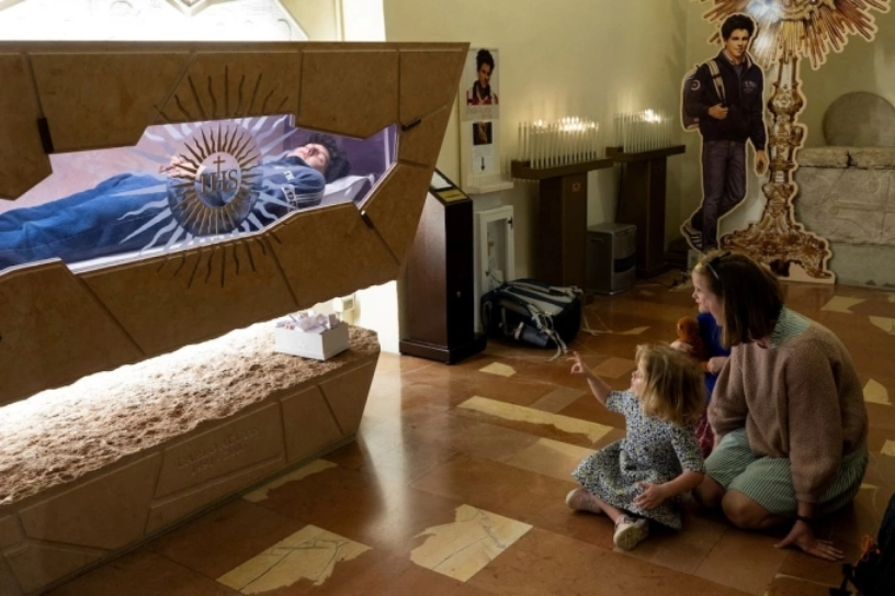 Người mẹ và con nhỏ tới thăm mộ phần của Carlo Acutis trong nhà thờ Santa Maria Maggiore ở Assisi, miền trung Italy, ngày 10/4. Ảnh: Reuters