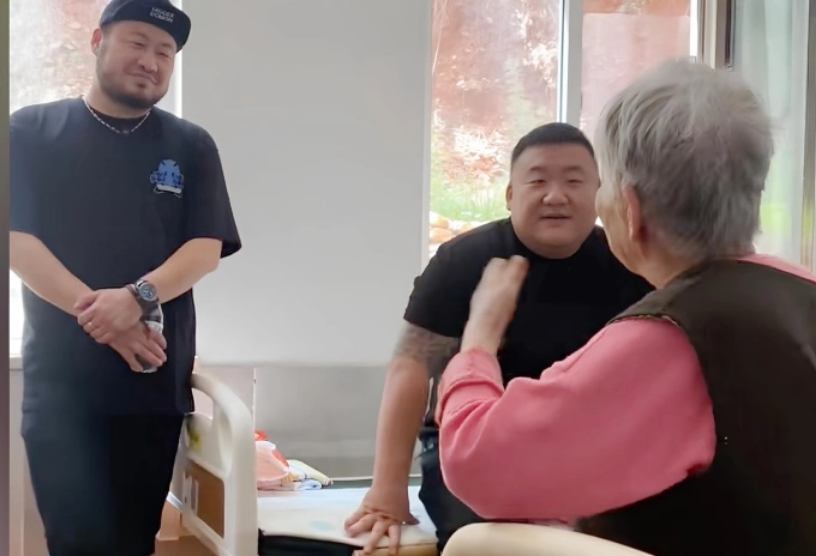 A Kai (ngồi giường) và cộng sự đang đến thăm hỏi một cụ bà ở Đại Liên, Trung Quốc tháng 9/2025. Ảnh: QQ