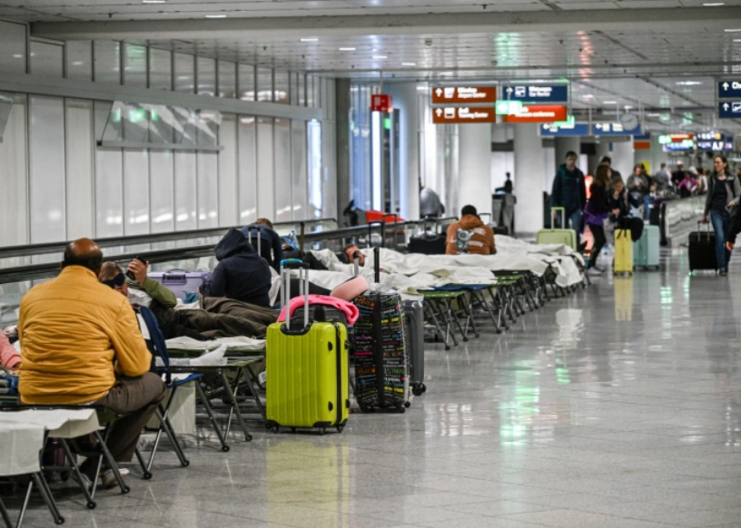 Hành khách nằm chờ ở sân bay Munich khi hàng loạt chuyến bay bị hủy hôm 2/10. Ảnh: Reuters