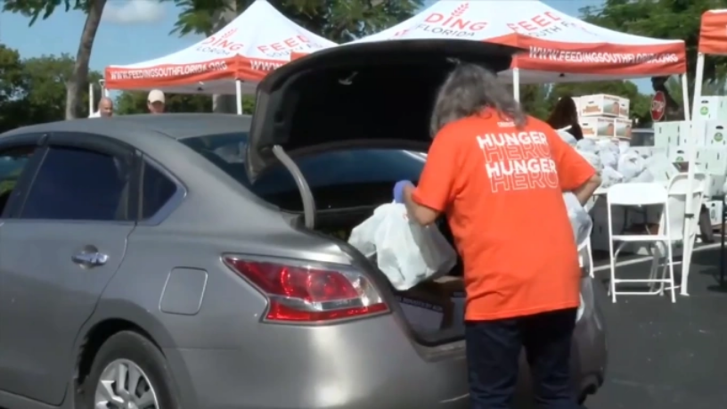 Tình nguyện viên Feeding South Florida chất thực phẩm hỗ trợ vào cốp xe của nhân viên liên bang, ngày 28/10. Ảnh: 7 News