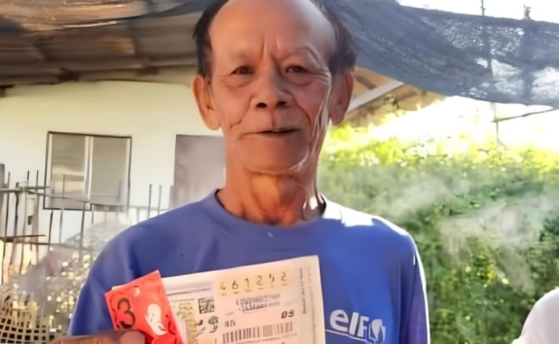 Ông Suthon, 68 tuổi, cầm tờ vé số độc đắc, tháng 12/2025. Ảnh: Khaosod
