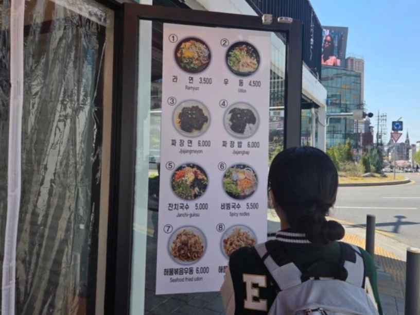 Một sinh viên đại học xem thực đơn bên ngoài nhà hàng ở quận Seodaemun, Seoul, Hàn Quốc, ngày 7/4. Ảnh: Korea Times