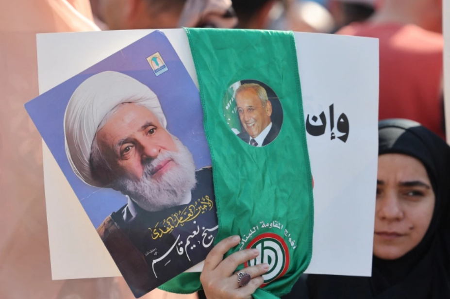 Một phụ nữ cầm ảnh thủ lĩnh Hezbollah Naim Qassem (trái) và Chủ tịch Quốc hội Lebanon Nabih Berri trong cuộc biểu tình ở thủ đô Beirut ngày 30/4. Ảnh: AFP